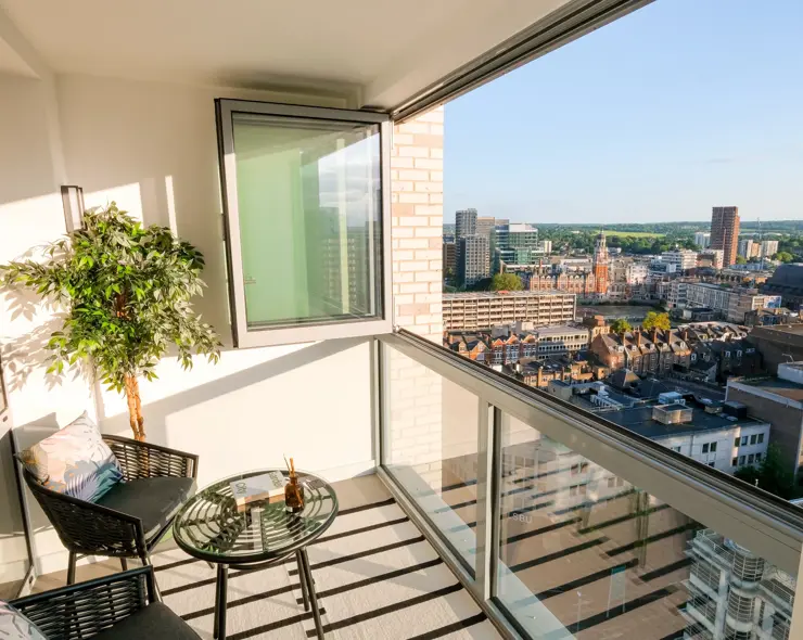 Winter garden with floor-to-ceiling windows, decorative planting, seating area and city views.
