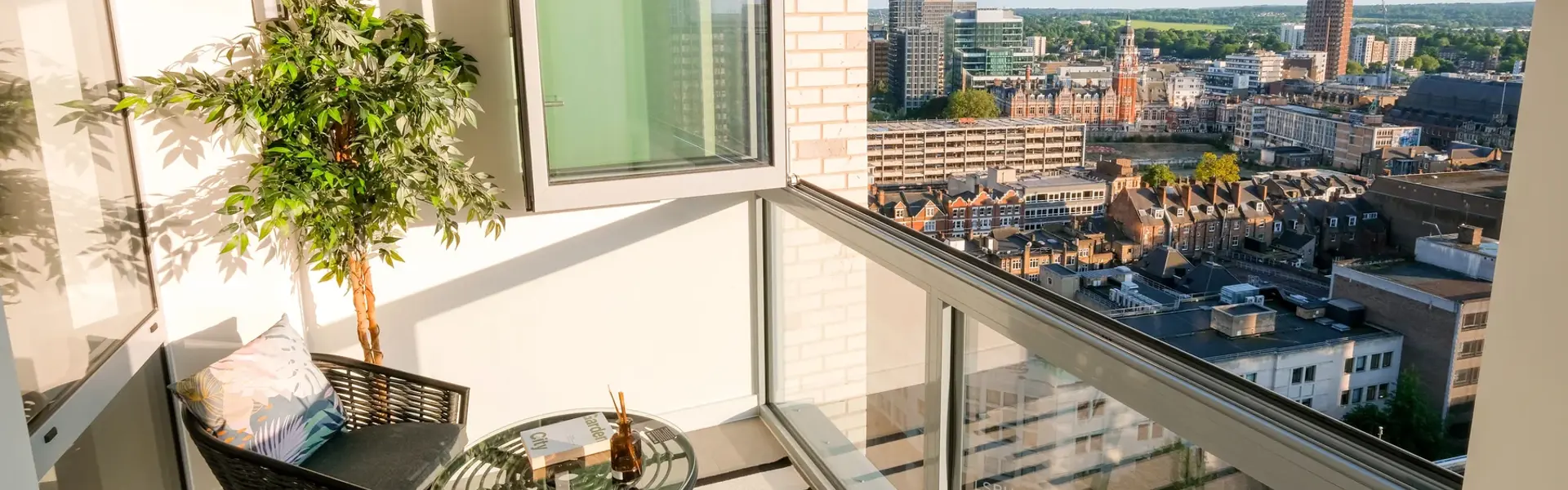 Winter garden with floor-to-ceiling windows, decorative planting, seating area and city views.
