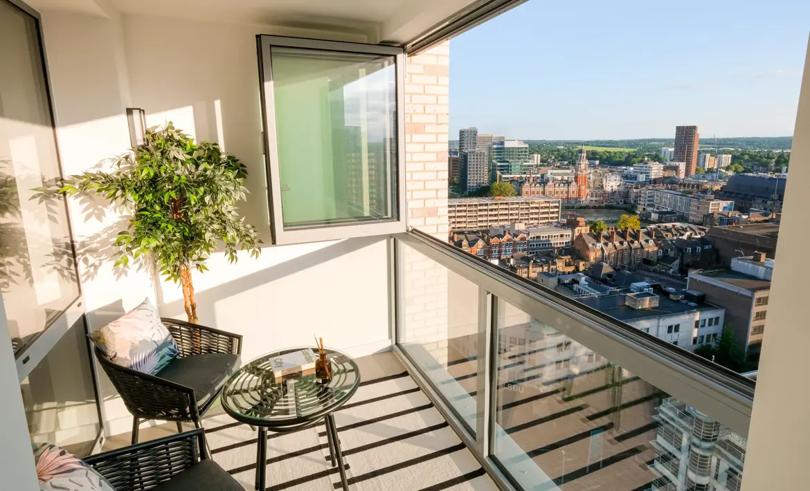 Winter garden with floor-to-ceiling windows, decorative planting, seating area and city views.