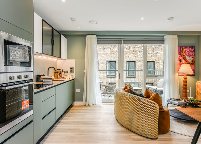 A bright and contemporary open-plan kitchen, with floor-to-ceiling glass doors to a private balcony.