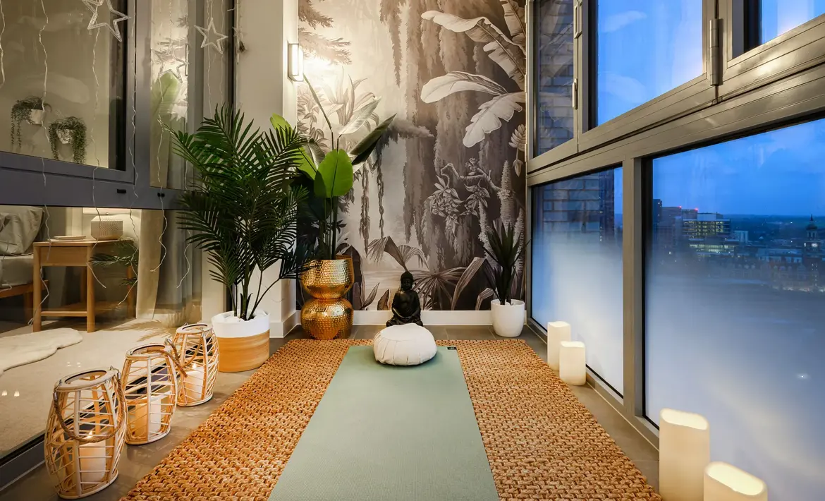 A winter garden with floor-to-ceiling windows, a yoga mat, indoor plants and a sweeping evening cityscape view.
